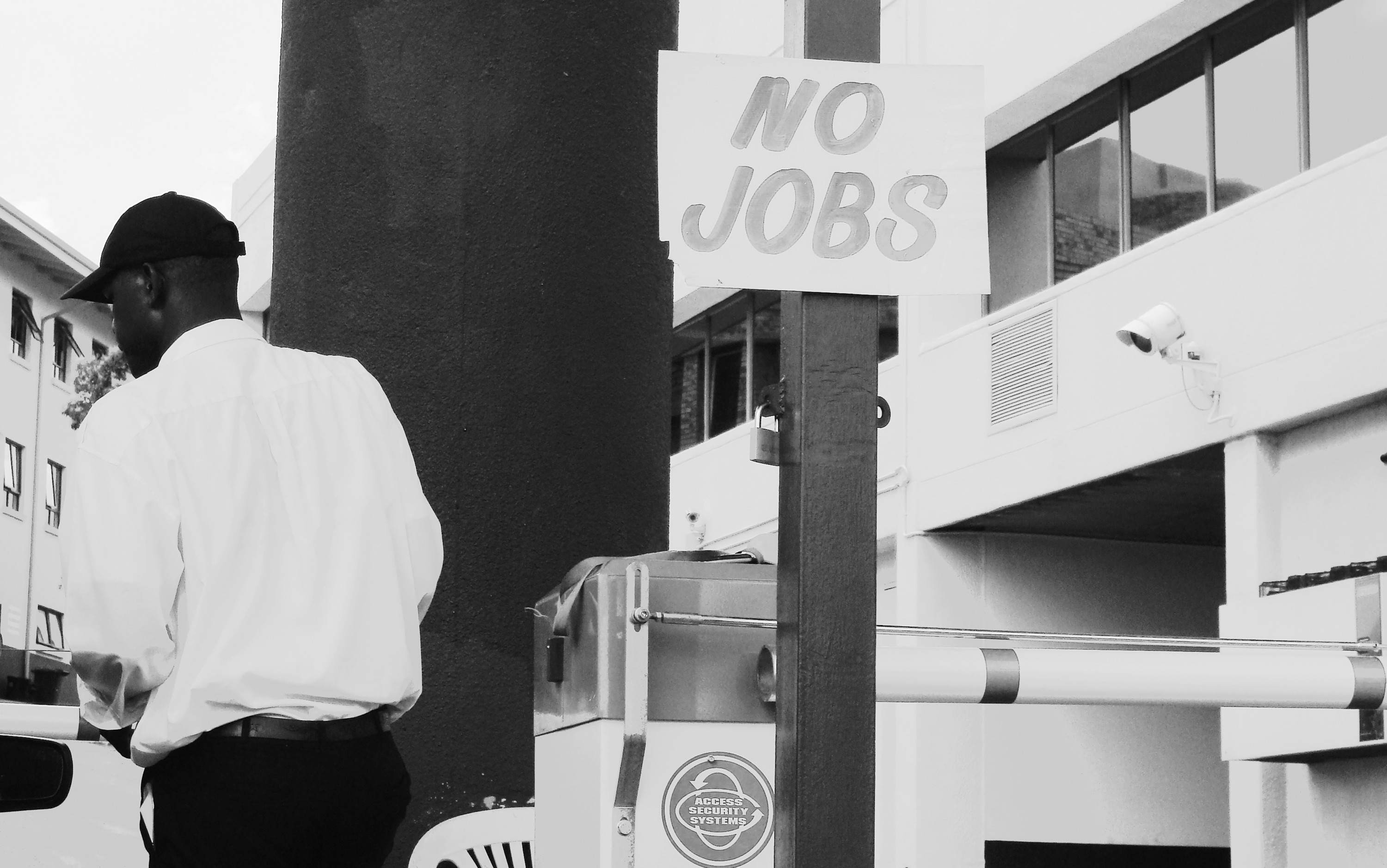 Worker walking by a sign reading 'nojobs'.